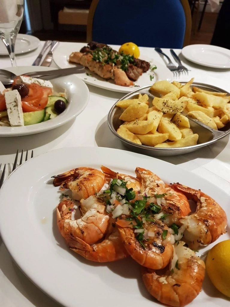 Grilled king prawns with herb salsa, fries and Greek salad