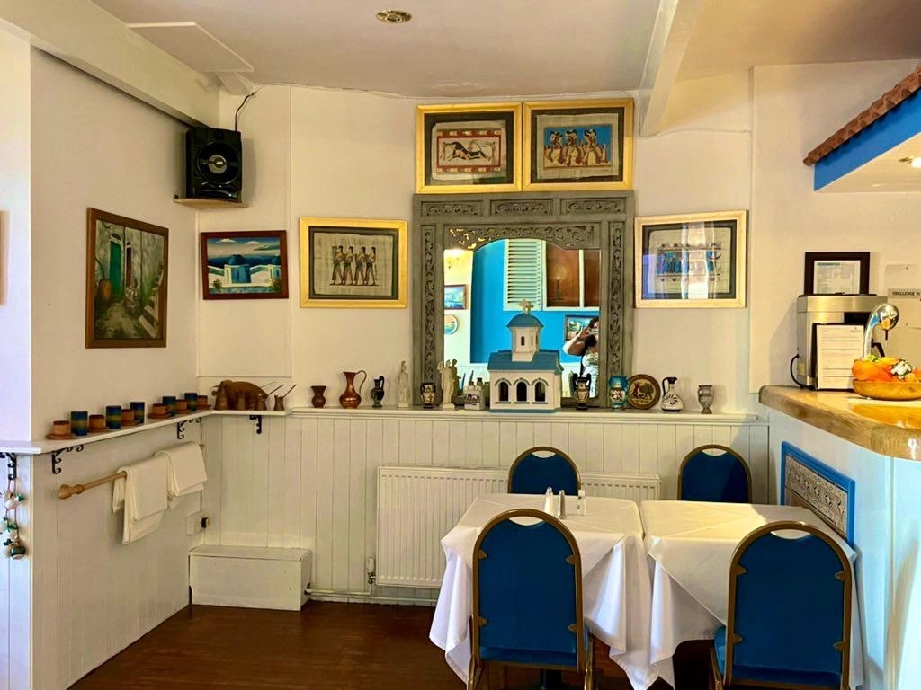 A quiet corner of the taverna with framed prints and Greek pottery