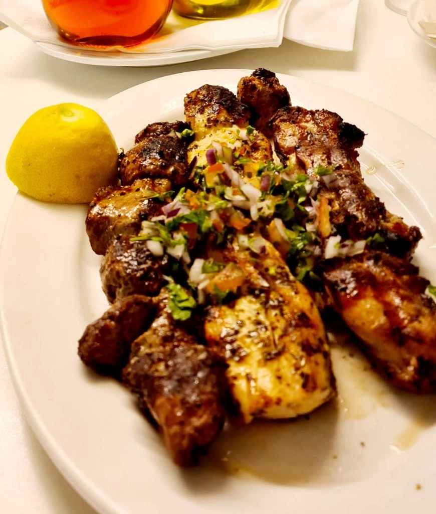 Charcoal-grilled souvlaki skewers with onion, tomato and lemon